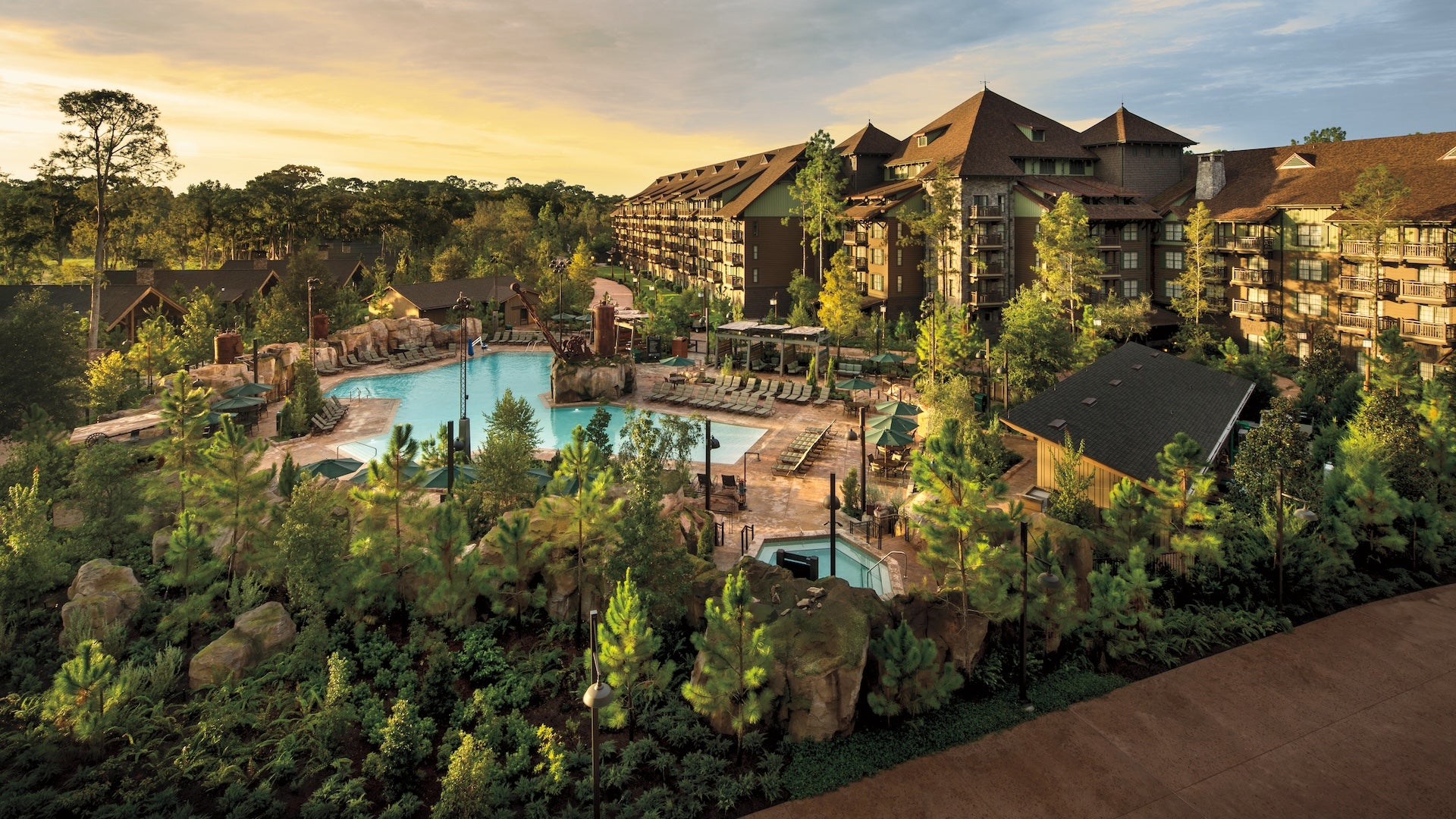 Exterior view of a resort with a pool and lots of alpine greenery